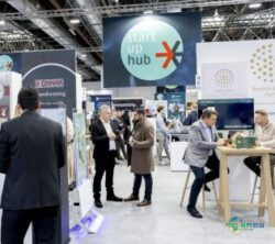 EuroShop初创企业中心热闹的展会场景：年轻企业、交谈中的参观者与展位，上方悬挂初创企业中心标识；版权：杜塞尔多夫展览/A. Wiese